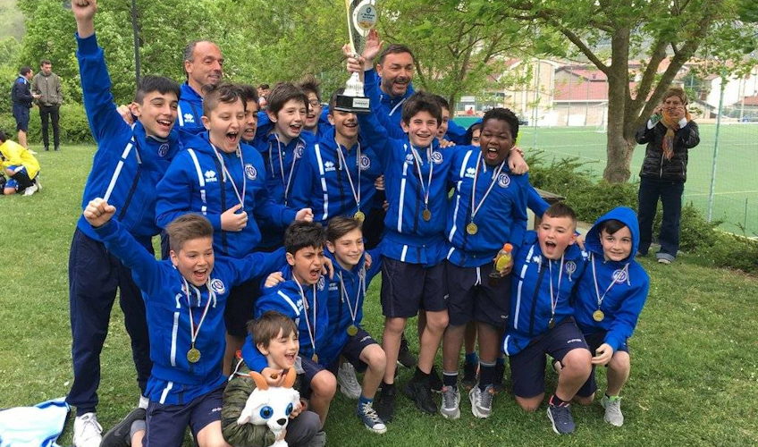 Youth soccer team in the US with medals and a trophy exuberantly celebrating their victory at a festival, with joy and pride.