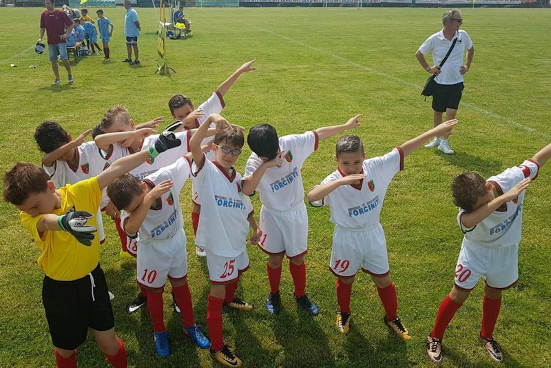 Youth football team celebrating victory on green pitch