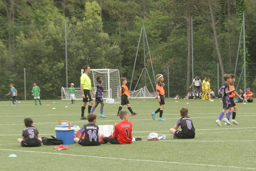 Unga fotbollsspelare i match med åskådare i bakgrunden, framhäver den livliga sportstämningen.