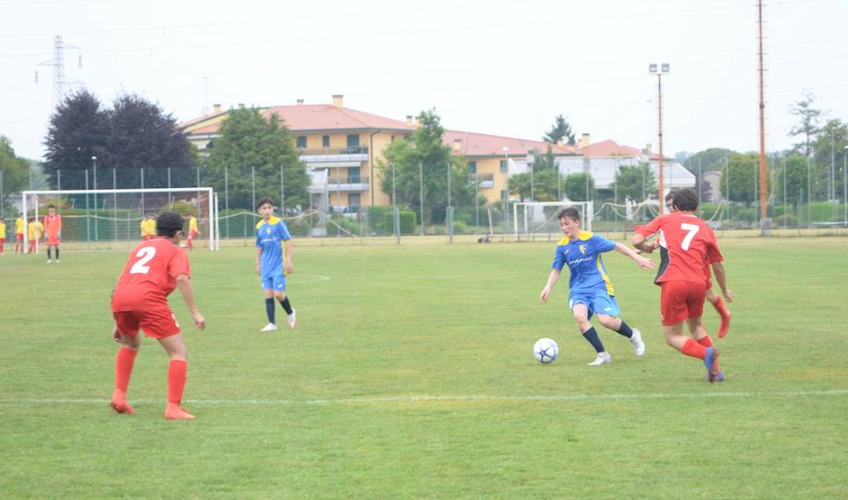 Jogadores de futebol com camisas vermelhas e azuis jogando em campo verde no torneio Trofeo Alto Adriatico