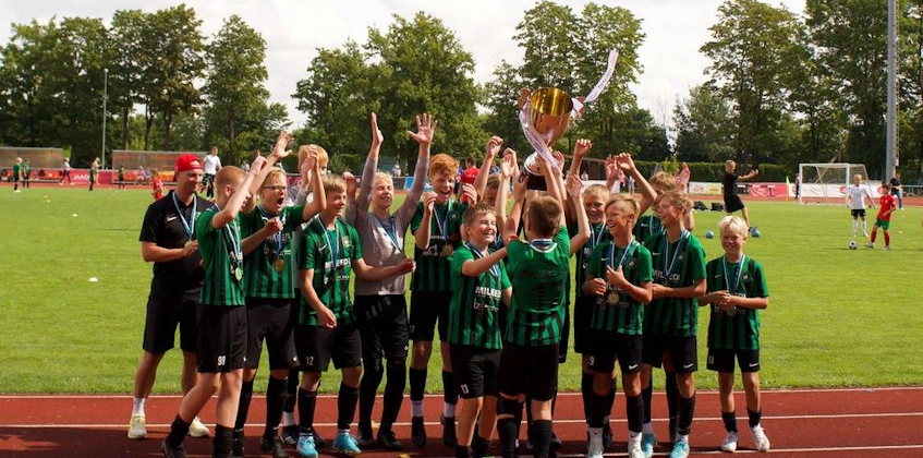 Noorte jalgpallurite meeskond tähistab Tartu turniiri võitu trofeega