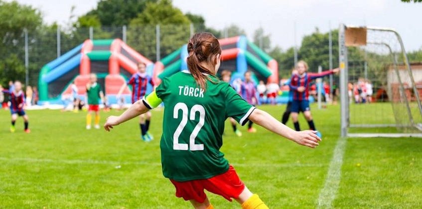 Kvindelig fodboldspiller nummer 22 i grøn trøje tager et skud under Laola Cup-turneringen