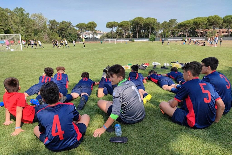 Equipo de fútbol juvenil en uniformes azules y rojos mirando un partido