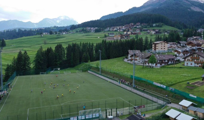 Meci de fotbal pentru copii la Festivalul Val di Fassa cu muntele în fundal