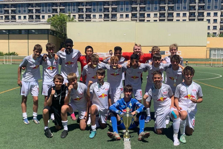 Winnaars van de Spain Esei Cup met trofee op voetbalveld