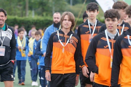 Xixón Esei Cup टूर्नामेंट में नारंगी-काली ट्रैकसूट में युवा फुटबॉलर