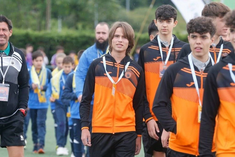 Jonge voetballers in oranje-zwarte trainingspakken op Xixón Esei Cup toernooi