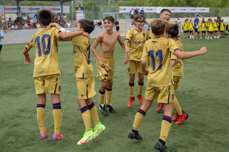 Youth soccer team in gold jerseys celebrating a victory on the field.