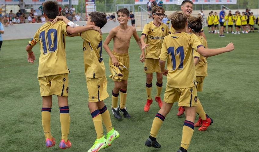 Nuorten jalkapallojoukkue kultaisissa paidoissa juhlii voittoa kentällä.
