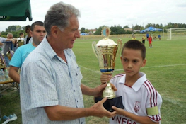 Menino recebe troféu de futebol no torneio Čin Čin Taça de Outono