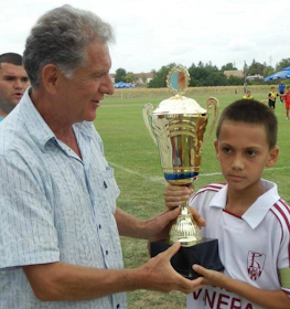 Menino recebe troféu de futebol no torneio Čin Čin Taça de Outono