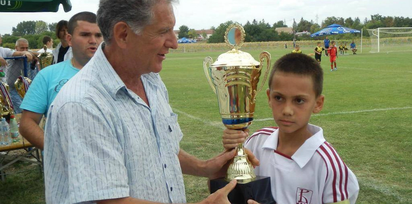 少年がČin Činオータムカップのサッカートーナメントでトロフィーを受け取る
