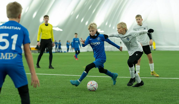 Lapset urheiluasusteissa pelaavat jalkapalloa iSport February Cup -turnauksessa