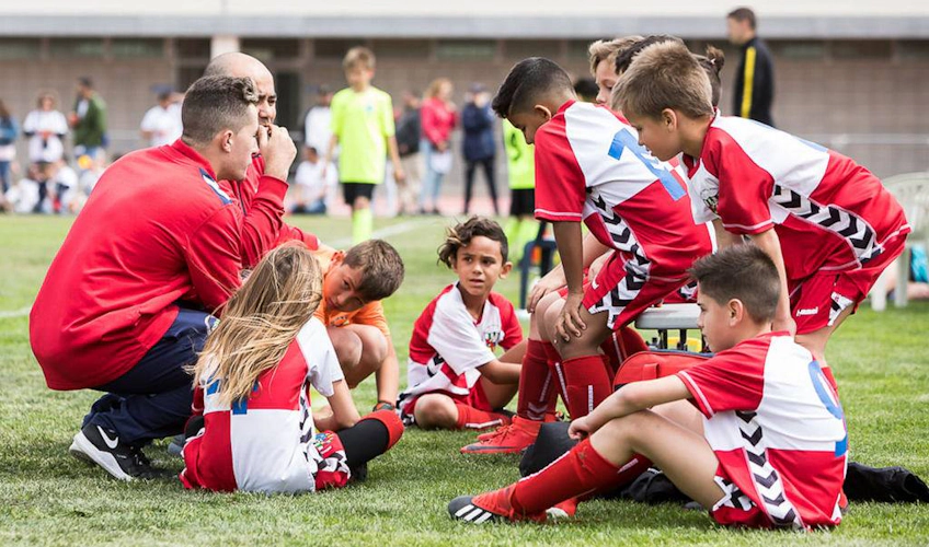 Coach discussing strategy with children's football team at Costa Daurada Verano Cup tournament