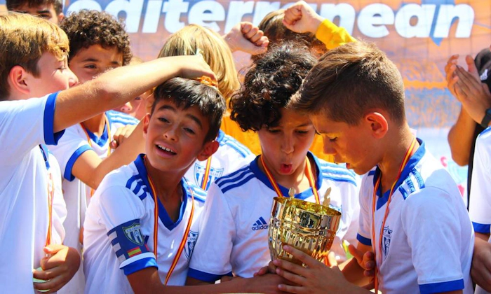 Unge fotballspillere kysser trofeet på Mediterranean Esei Cup-turneringen