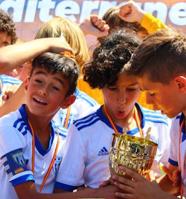 Jovens futebolistas beijando o troféu no torneio Mediterranean Esei Cup