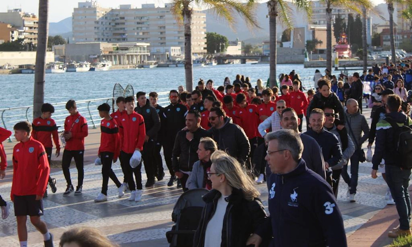 Groep voetbalteams loopt op een zeeboulevard tijdens het Mediterranean Esei Cup toernooi