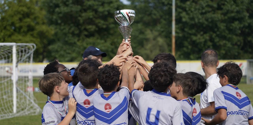 年轻的足球运动员在足球场上举起奖杯，团队胜利庆祝