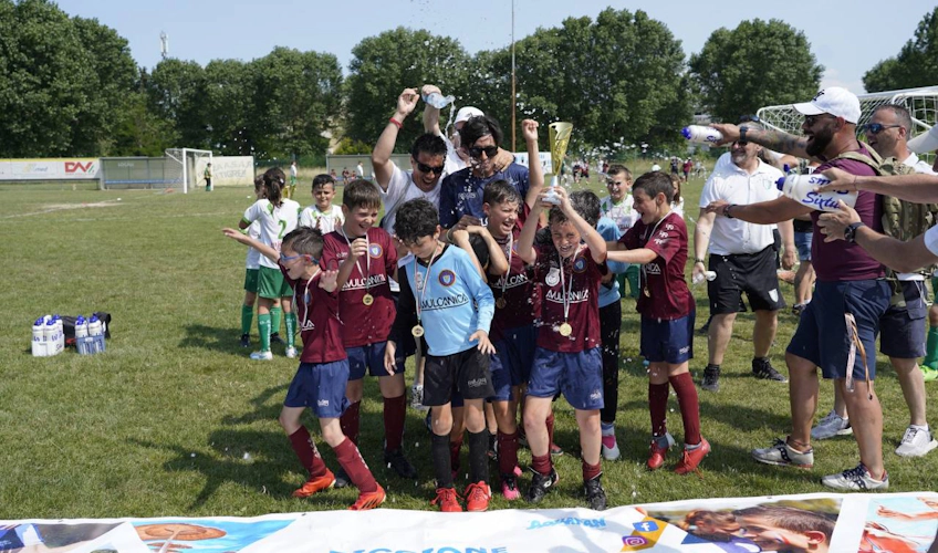 Children's football team celebrating victory with trophy at Riccione Aquafan Trophy tournament