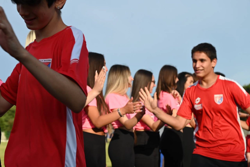 Des adolescents en maillots rouges et roses se saluent joyeusement au tournoi de football Trofeo Mar Tirreno