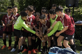 트로피를 들고 야외에서 축하하는 청소년 축구 팀
