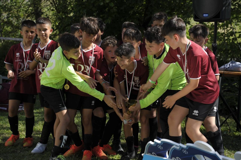 트로피를 들고 야외에서 축하하는 청소년 축구 팀