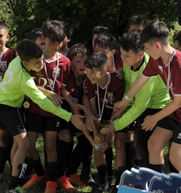 Equipo juvenil de fútbol celebrando con un trofeo al aire libre