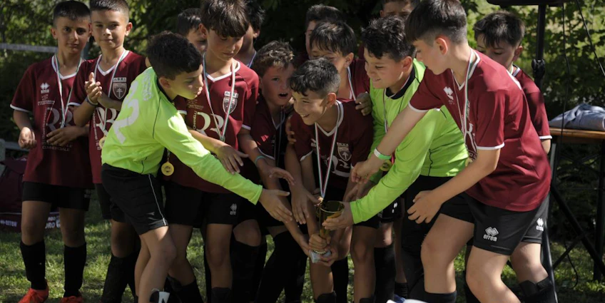 Ifjúsági futballcsapat ünnepel egy trófeával a szabadban