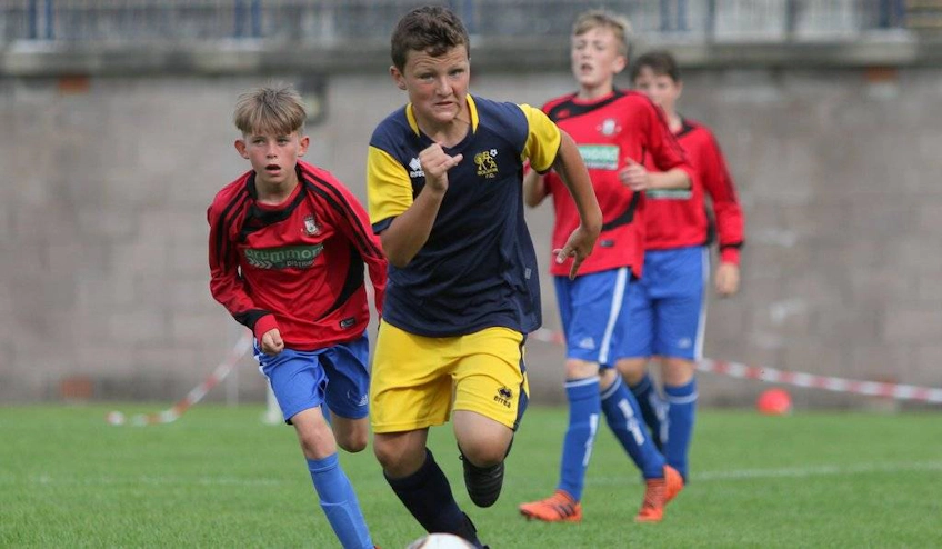 द एडिनबर्ग कप टूर्नामेंट में गेंद के लिए प्रतिस्पर्धा करते युवा फुटबॉल खिलाड़ी