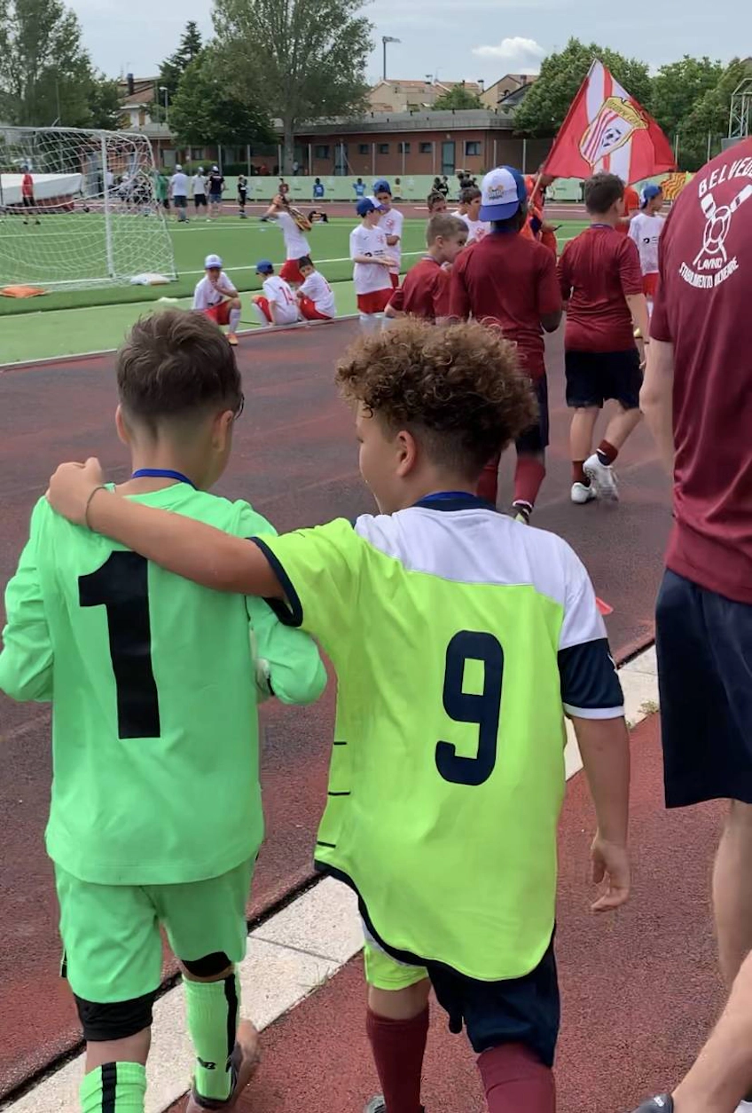两个穿着足球服的孩子在里维埃拉杯足球锦标赛中手拉手行走