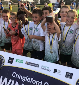 Jóvenes futbolistas celebran con trofeo en Cringleford.