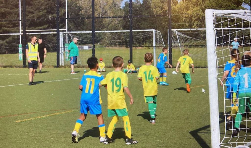Partido de fútbol juvenil en Copa Cringleford, niños jugando.