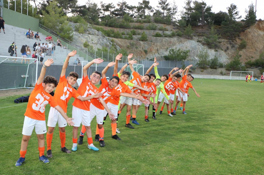 Lasten jalkapallojoukkue oransseissa pelipaidoissa iloitsee Platres Football Festival June -turnauksessa