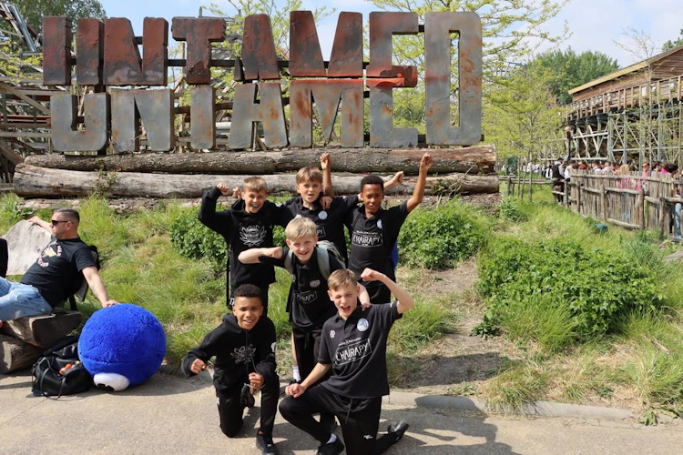 Kinderfußballmannschaft vor dem 'UNTAMED'-Schild beim Walibi Cup Turnier im Mai