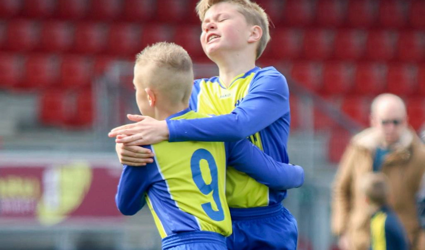 Młodzi piłkarze przytulają się na turnieju piłkarskim Walibi Cup June