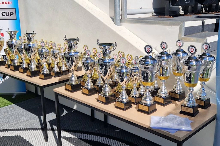 An array of soccer trophies displayed on a table at a football tournament