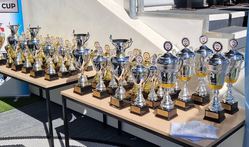 Uma variedade de troféus de futebol exibidos em uma mesa em um torneio de futebol