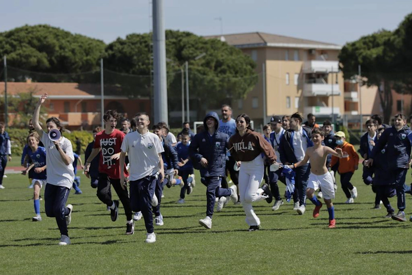 बच्चे Trofeo Delle Terme टूर्नामेंट में फुटबॉल मैदान पर दौड़ रहे हैं