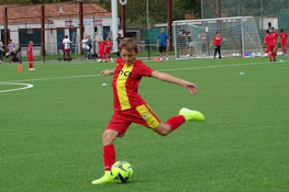 Мальчик в красной форме бьёт по футбольному мячу на турнире Ixina Cup
