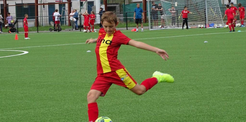 Мальчик в красной форме бьёт по футбольному мячу на турнире Ixina Cup