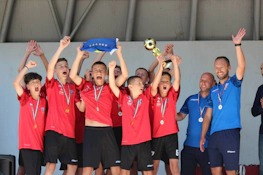 Νεαροί ποδοσφαιριστές με κόκκινα πουκάμισα πανηγυρίζουν τη νίκη στο τουρνουά