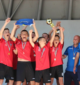 Unga fotbollsspelare i röda tröjor firar en seger i turneringen