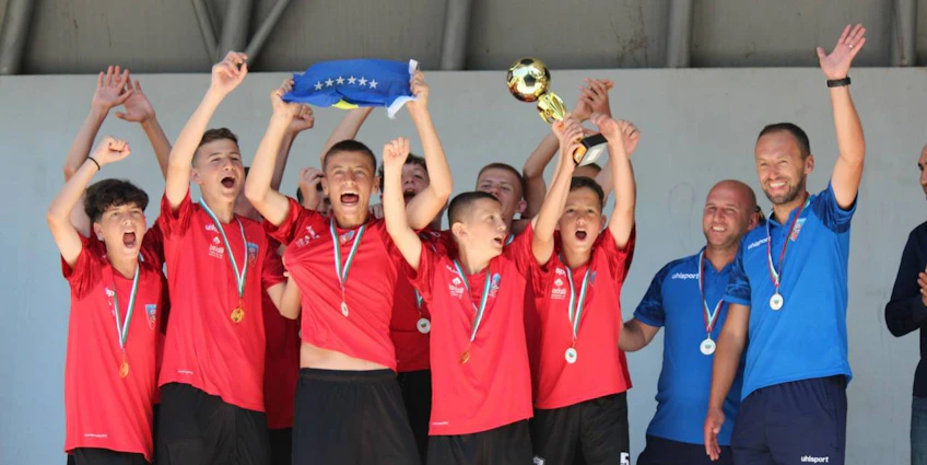 Jovens futebolistas em camisas vermelhas comemorando vitória no torneio