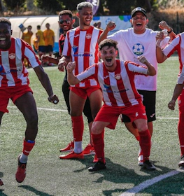 Piłkarze w czerwono-białych pasiastych strojach świętują zwycięstwo na boisku