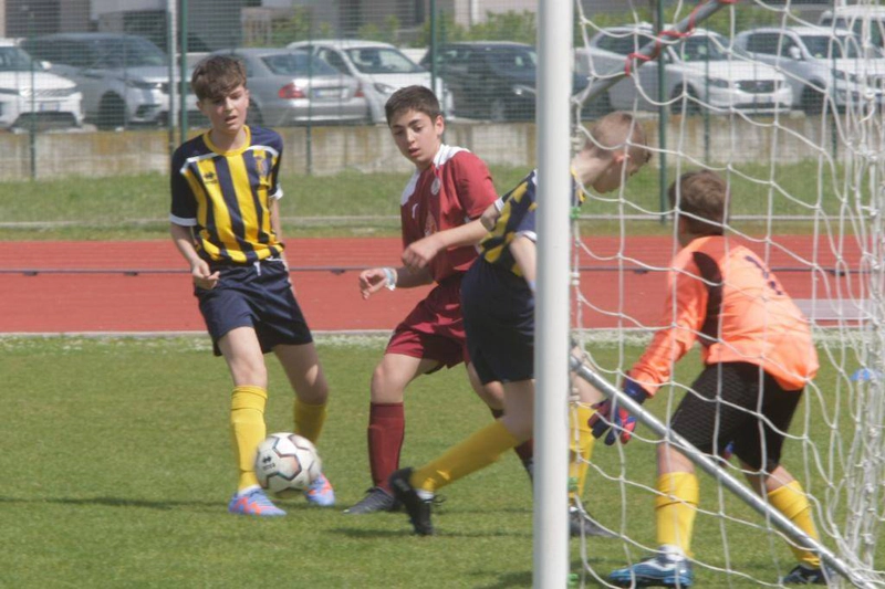 Tenåringsfotballspillere engasjert i et spill, målvakt klar ved målstolpen