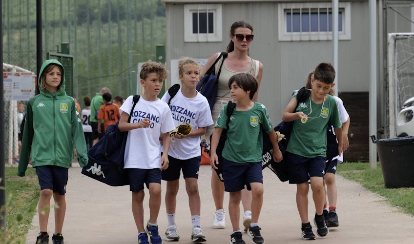 Lapset jalkapallovarusteissa kävelevät valmentajan kanssa pelin jälkeen