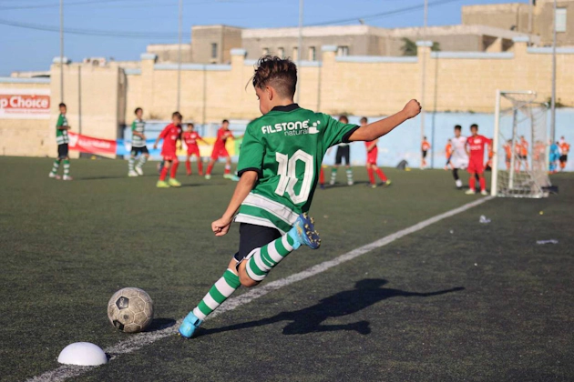 身穿10号绿色球衣的青少年在U14 KHS杯足球赛中踢球