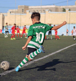 Młody gracz numer 10 w zielonym stroju kopie piłkę na turnieju U14 KHS Cup
