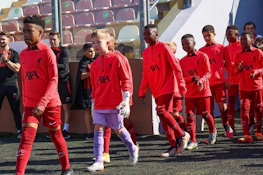 赤いユニフォームを着た子供のサッカーチームがU10 KHSカップのフィールドに入る