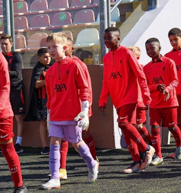 Lasten jalkapallojoukkue punaisissa peliasuissa kävelee kentälle U10 KHS Cupissa